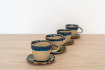 Set of four cups with saucers on a wooden table. High quality photo. Pottery, handmade
