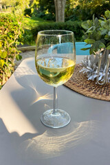 Glass of white wine on a table in the garden. Close-up