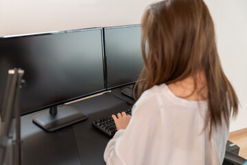 パソコンで編集作業をする女性　後ろ姿