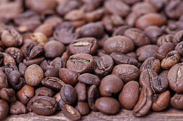 Roasted coffee beans on a wooden background macro photo.