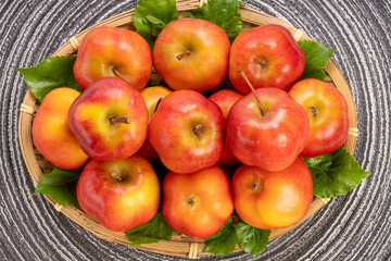 Fresh red star apple in Bamboo basket on Brown background, Korea Star Apple in wooden basket on Brown placemat.