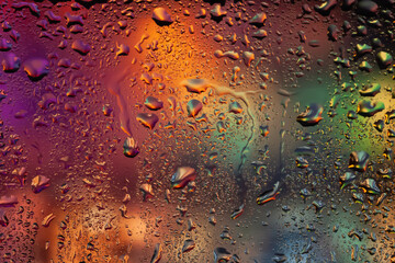 Drops of water on the glass. Drops of rain on the window. Abstract background. Multi-colored spots. Texture of drops. Selective focus
