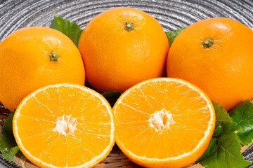 Fresh Orange fruit on wooden basket on wooden background, Japanese Orange with slices on wooden Background.