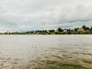 Traveling along the Rhine River with scenic views of the medieval town of Budenheim, Germany. Views of colorful European style architecture and vineyards on the sloping land.