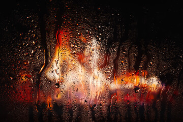 Raindrops on the window. Water drops on glass. Abstract background. Flame of fire. Texture of drops
