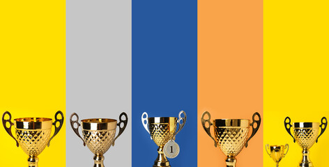 Collage of golden trophy cups and medal on color background