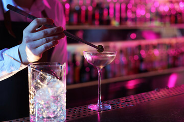 Bartender adding olive into Martini cocktail at bar counter, closeup. Space for text