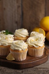 Obraz na płótnie Canvas Delicious cupcakes with white cream and lemon zest on wooden table, closeup