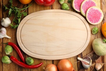 Empty cutting board and different vegetables on wooden table, flat lay. Space for text