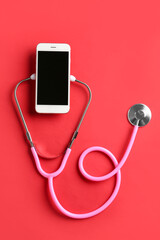 Stethoscope and mobile phone on red background