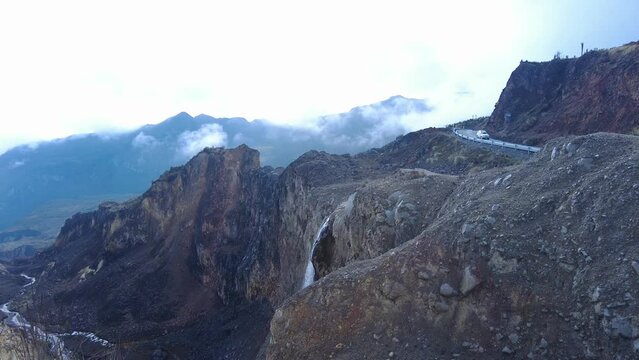 Young woman raisng her arms in the top of a mountain with clouds and waterwall on the Colombian nevado or paramo. Trekking and adventure footage with freedom spirit.