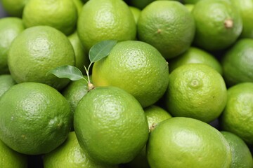 Many fresh limes with green leaves as background, closeup