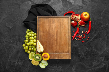 Composition with wooden cutting board, fresh fruits and chili peppers on dark background