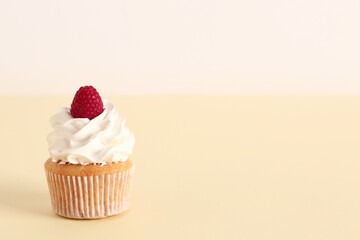Tasty raspberry cupcake on beige background