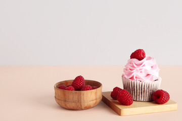 Tasty raspberry cupcake and fresh berries on beige background