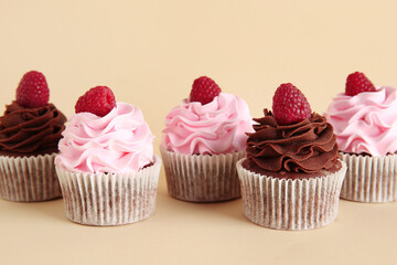 Tasty cupcakes with raspberries on beige background