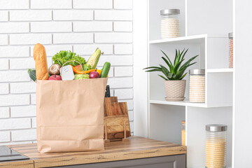 Paper bag with different products and utensils on counter in kitchen