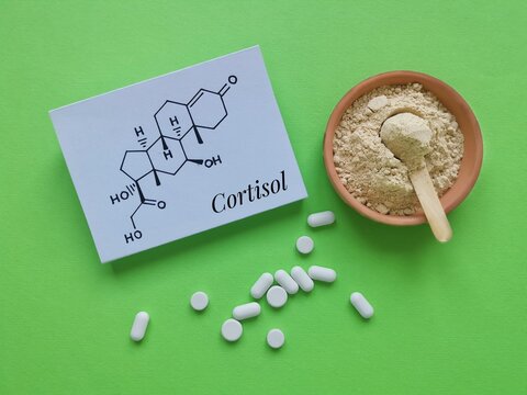 Structural chemical formula of cortisol (a steroid hormone) with white pills and ashwagandha powder. Cortisol is a stress hormone. Ashwagandha food supplements for stress and anxiety, medical concept