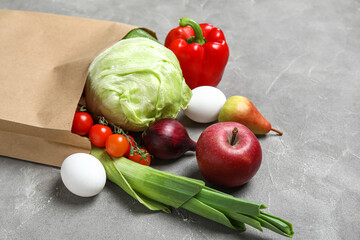 Paper bag full of fresh vegetables and fruits on grunge grey background