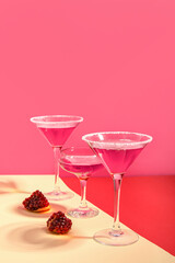 Glasses of Cosmopolitan cocktail with pomegranate on colorful background