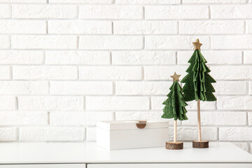 Cabinet with Christmas decor near white brick wall