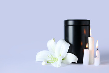 Mortuary urn, burning candles and beautiful lily flower on grey background
