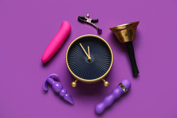 Alarm clock with different toys on purple background. Time for sex