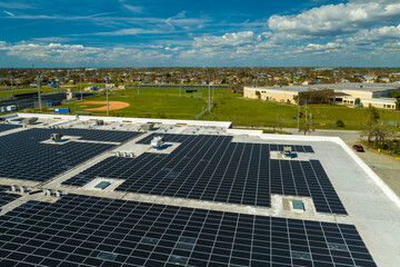 Aerial view of solar power plant with blue photovoltaic panels mounted on industrial building roof for producing green ecological electricity. Production of sustainable energy concept