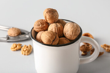 Mug of tasty walnuts on grey background