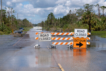Flooded street in Florida after hurricane rainfall with road closed signs blocking driving of cars....