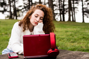 Obraz premium Redhead woman studying outdoors with her computer and mobile phone