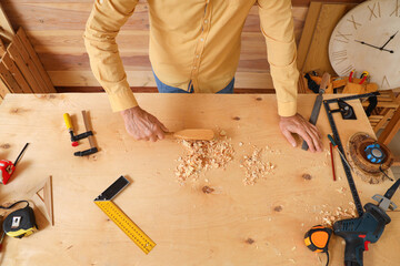 Mature carpenter sweeping filings with brush on table in shop, top view