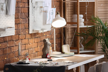 Jeweler's workplace with glowing lamp, sketches and laptop in workshop