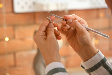 Female jeweler examining earring in workshop, closeup