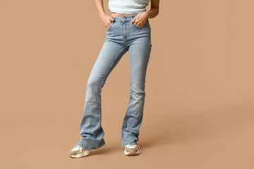 Beautiful young Asian woman in stylish jeans on brown background, closeup