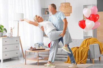 Mature couple dancing at home on Valentine's Day - obrazy, fototapety, plakaty