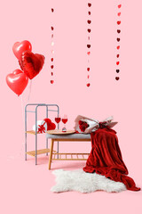Grey bench with glasses of wine, roses and decorations for Valentine's Day celebration on pink...