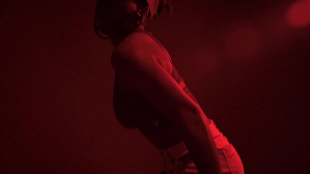 Slow motion of black woman dancer performs dancehall under red lights	