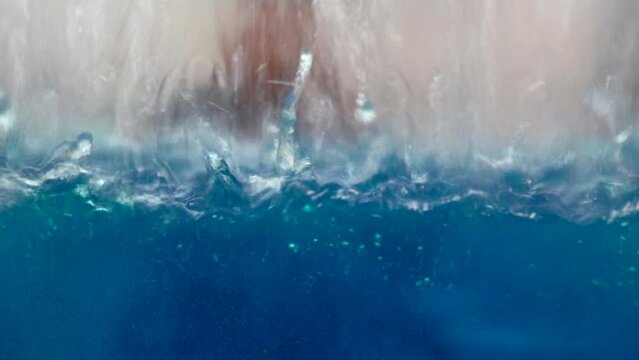 industrial background with a transparent reservoir being filled with liquid. Media. Water drops falling down and making ripples.