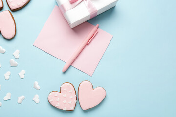 Heart shaped cookies with gift box and paper on blue background. Valentine's day celebration