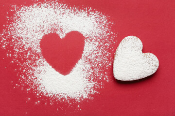 Heart made of sugar powder and sweet cookie on red background. Valentine's day celebration