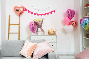 Chest of drawers with bouquet of roses, burning candles and heart-shaped balloons in living room....