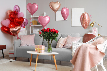 Interior of festive living room with grey sofa, heart-shaped balloons and bouquet of roses on...