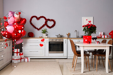 Interior of light kitchen with heart-shaped balloons and bouquet of roses on dining table....