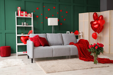 Interior of festive living room with grey sofa, bouquet of roses and heart-shaped balloons. Valentine's Day celebration