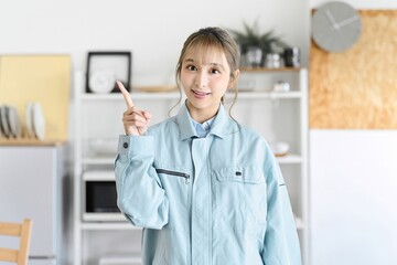 指差しをする作業服を着た自宅へ伺う職業の女性
