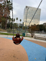 Child on Swing with Urban Backdrop