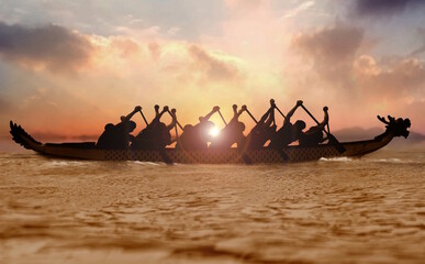 Group of people paddling dragon boat at sunset