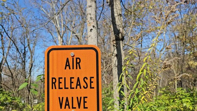 Air release valve sign on bright orange background with forest behind
