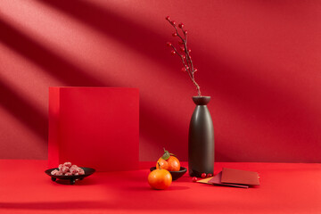 Close-up of a red gift box, a plate of jam, tangerines, lucky money envelopes and a vase of...